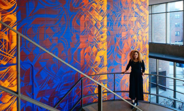 Mittal Institute Arts Program Manager Sneha Shrestha in front of one of her recent murals. Image provided by Sneha Shrestha